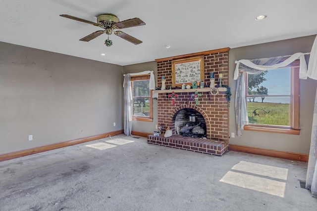 unfurnished living room with ceiling fan, light colored carpet, a wealth of natural light, and a brick fireplace