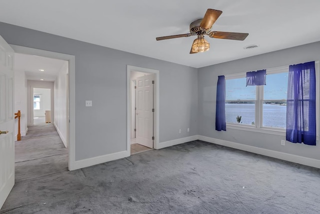 carpeted empty room with ceiling fan and a water view