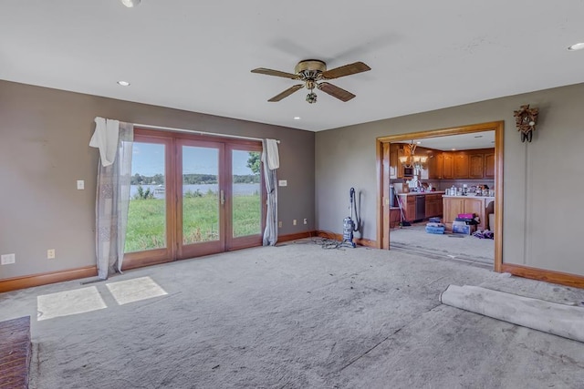 unfurnished living room with light carpet and ceiling fan with notable chandelier