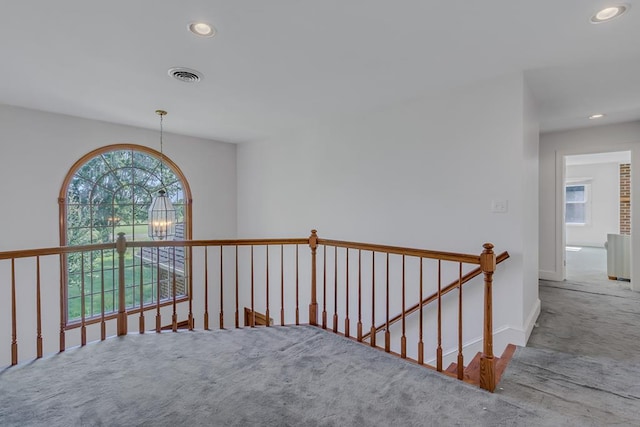 hallway with carpet flooring and a chandelier