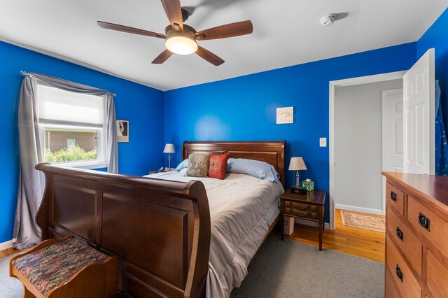 bedroom featuring baseboards, wood finished floors, and a ceiling fan