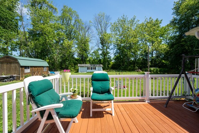 wooden deck featuring an outbuilding, a shed, and a lawn