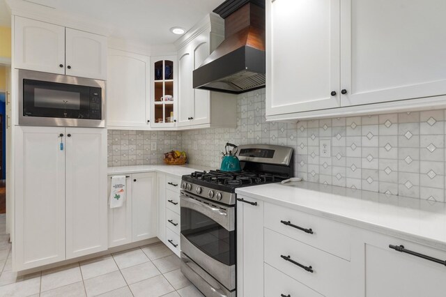 kitchen with wall chimney range hood, light countertops, stainless steel gas stove, and built in microwave