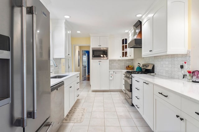 kitchen with light countertops, a sink, light tile patterned flooring, white cabinets, and appliances with stainless steel finishes