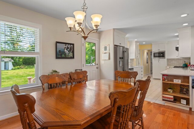 dining area featuring light wood finished floors, a wealth of natural light, and an inviting chandelier
