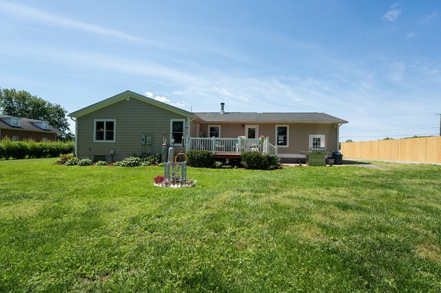 rear view of property with a lawn, fence, and a deck
