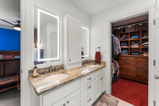 bathroom featuring double vanity, ceiling fan, a sink, and a walk in closet