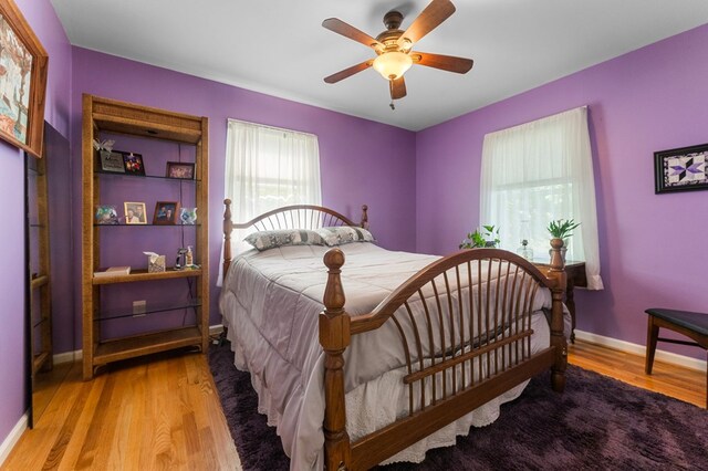 bedroom with a ceiling fan, baseboards, and wood finished floors