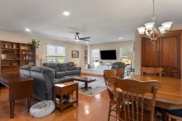 living area with ceiling fan with notable chandelier, light wood-style flooring, and recessed lighting