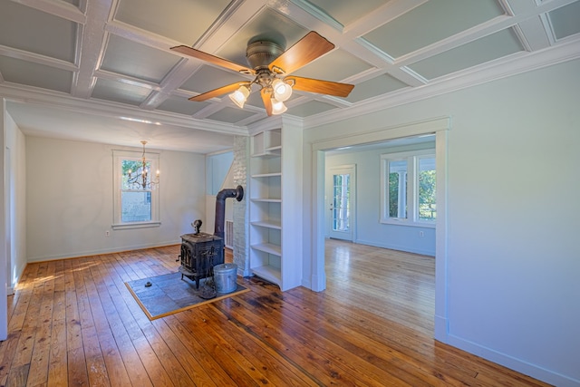 interior space featuring a wood stove, built in shelves, coffered ceiling, wood-type flooring, and ceiling fan with notable chandelier