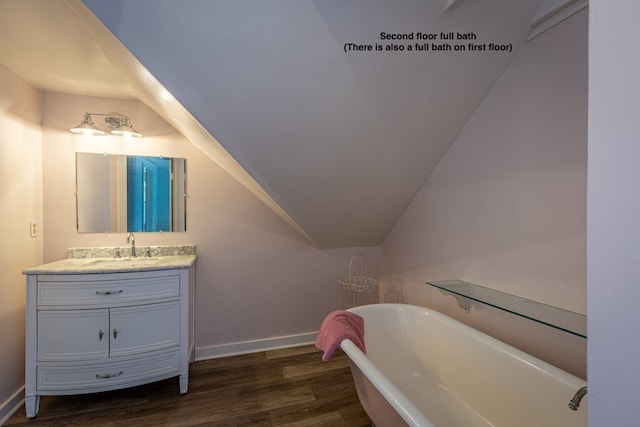 bathroom featuring vanity, hardwood / wood-style flooring, vaulted ceiling, and a bathtub