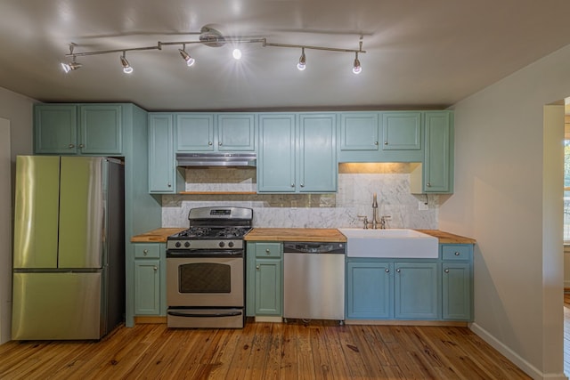 kitchen with decorative backsplash, appliances with stainless steel finishes, sink, light hardwood / wood-style flooring, and butcher block counters