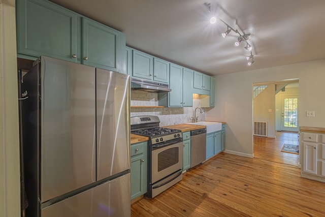 kitchen featuring backsplash, track lighting, sink, light hardwood / wood-style floors, and stainless steel appliances