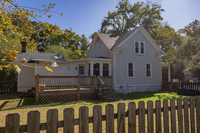 back of property with a deck and a yard