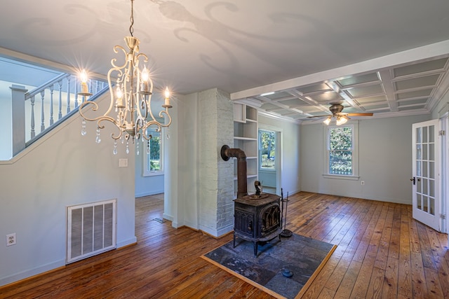 unfurnished living room with coffered ceiling, ceiling fan with notable chandelier, beam ceiling, hardwood / wood-style floors, and a wood stove