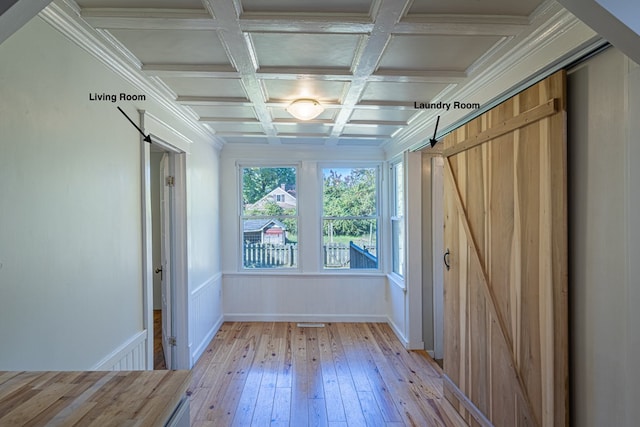 spare room featuring coffered ceiling, a barn door, beamed ceiling, crown molding, and light hardwood / wood-style floors