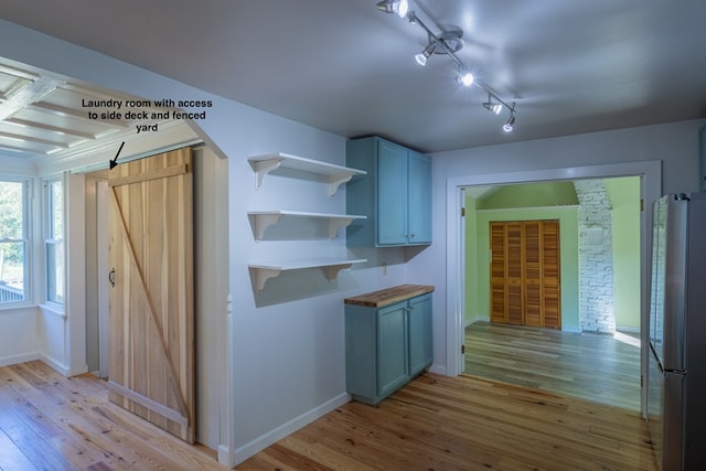 kitchen with stainless steel fridge, light wood-type flooring, rail lighting, and wooden counters