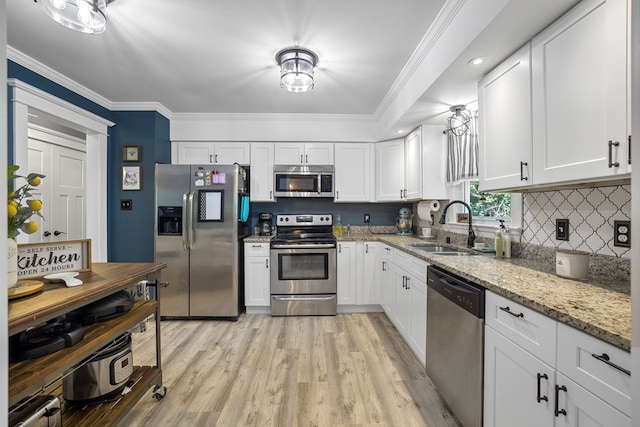 kitchen with white cabinetry, sink, stainless steel appliances, light stone counters, and crown molding