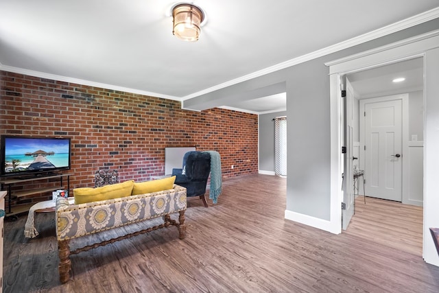 living room with light wood-type flooring, ornamental molding, and brick wall