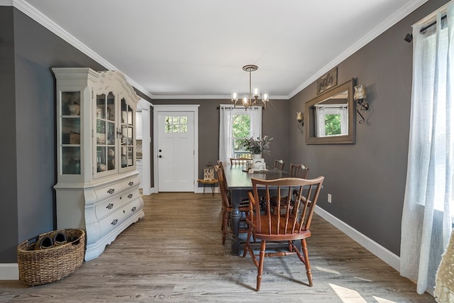 dining space with hardwood / wood-style floors, crown molding, and a chandelier