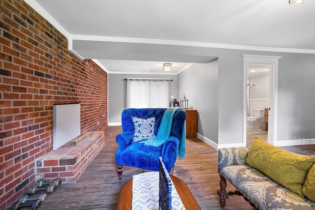 living room with hardwood / wood-style floors, brick wall, and ornamental molding