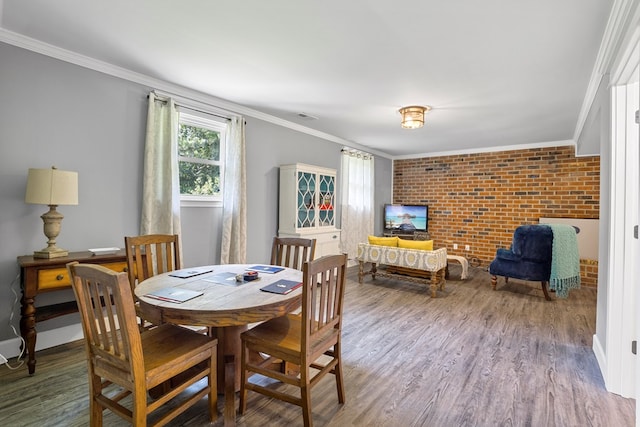 dining space featuring hardwood / wood-style floors, crown molding, and brick wall