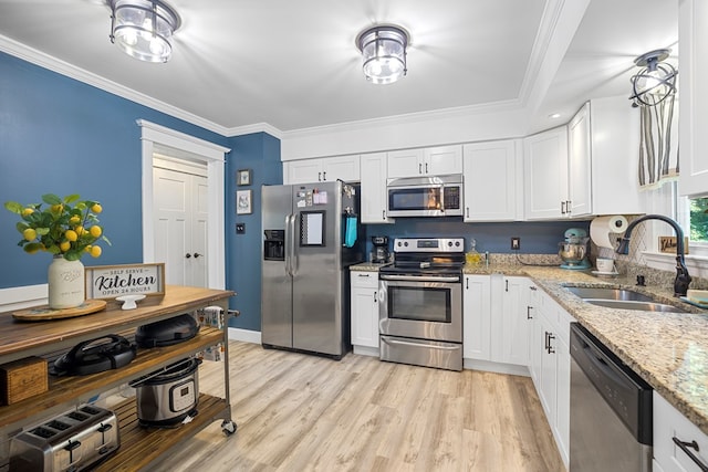 kitchen with white cabinets, sink, ornamental molding, light stone counters, and stainless steel appliances