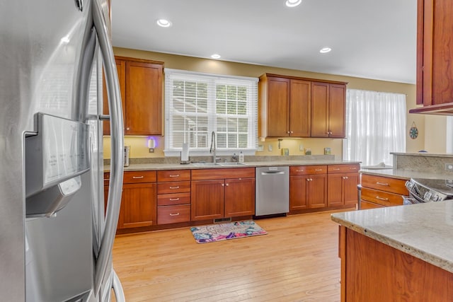 170 Rappa Run Rd, Topping, VA 23169 - kitchen featuring stainless steel appliances, a sink, light wood-style floors, light stone countertops, and brown cabinetry
