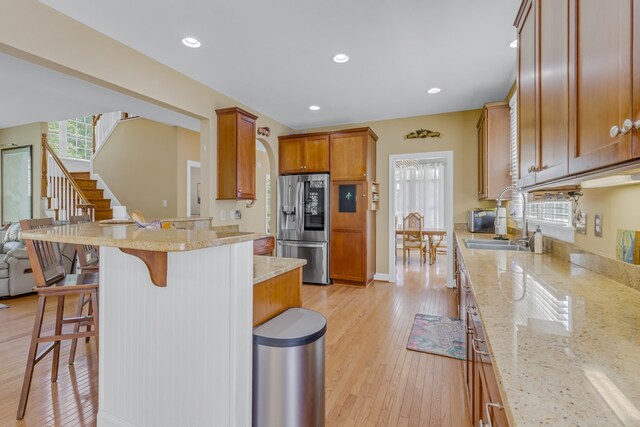 170 Rappa Run Rd, Topping, VA 23169 - kitchen featuring stainless steel fridge with ice dispenser, a kitchen bar, a sink, light stone counters, and light wood-style flooring