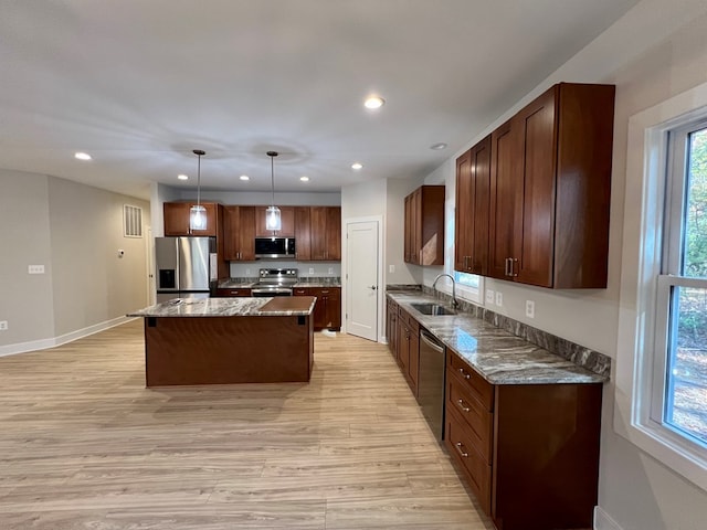 kitchen with stone counters, appliances with stainless steel finishes, sink, hanging light fixtures, and a center island