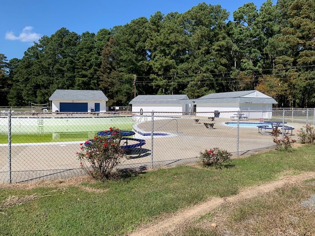 view of pool featuring a garage, an outdoor structure, and a lawn