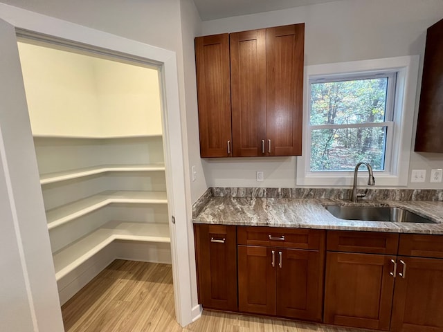 kitchen featuring sink, light stone countertops, and light wood-type flooring