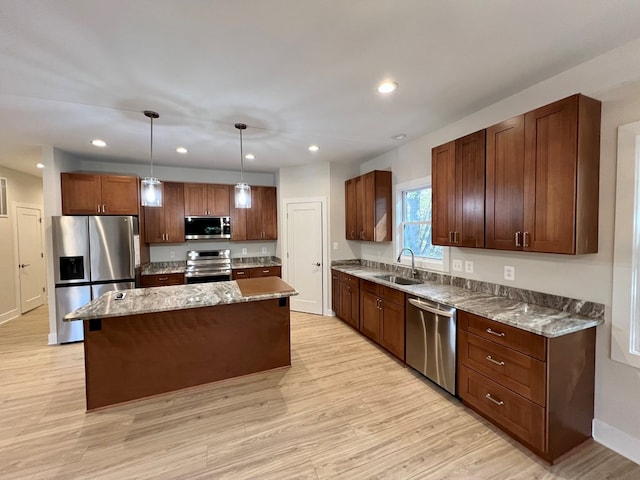 kitchen featuring pendant lighting, sink, appliances with stainless steel finishes, a kitchen island, and light wood-type flooring