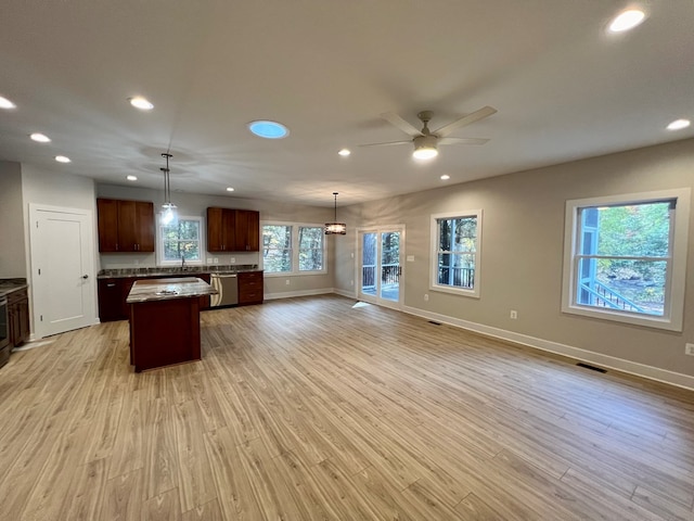 kitchen with decorative light fixtures, a center island, dishwasher, and light wood-type flooring