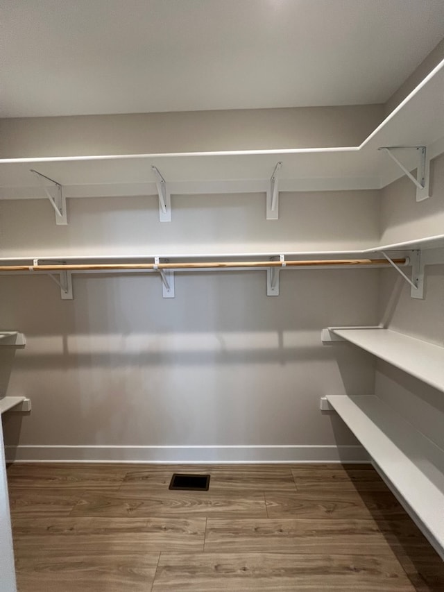 walk in closet with dark hardwood / wood-style floors