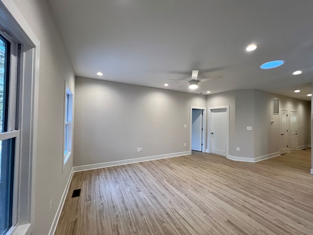 spare room featuring a healthy amount of sunlight, ceiling fan, and light hardwood / wood-style flooring