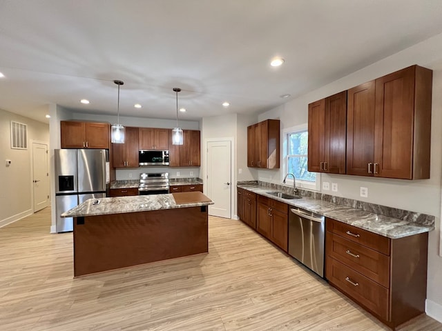 kitchen with a kitchen island, decorative light fixtures, sink, light hardwood / wood-style floors, and stainless steel appliances