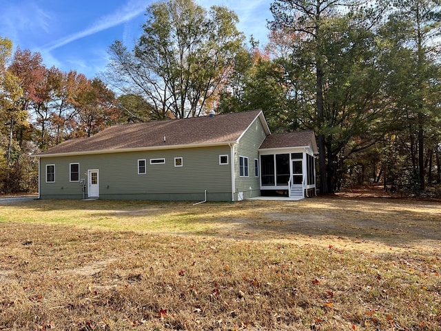 back of property with a lawn and a sunroom