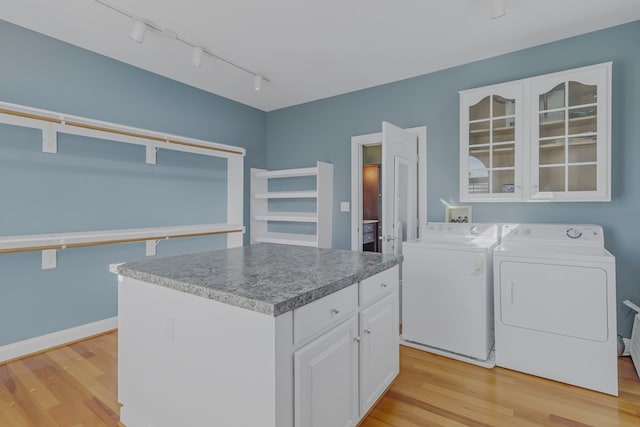 clothes washing area with cabinets, independent washer and dryer, and light wood-type flooring