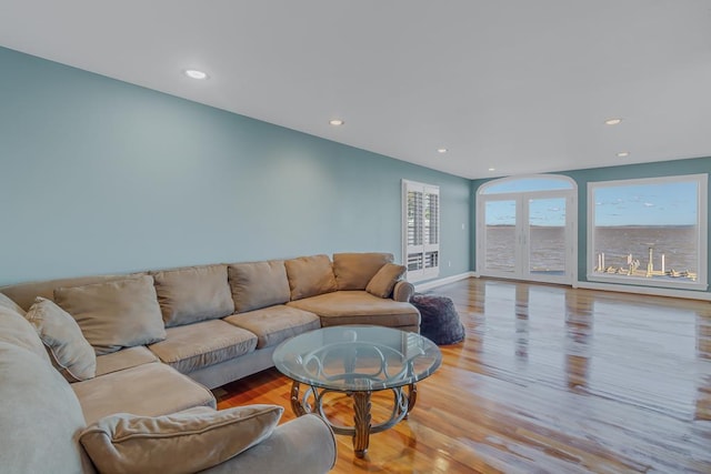 living room featuring a water view, light hardwood / wood-style floors, and french doors