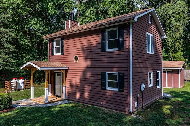 rear view of house with a yard and a storage unit