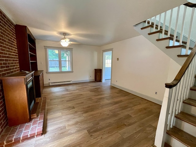 unfurnished living room featuring hardwood / wood-style floors, ceiling fan, a baseboard heating unit, and brick wall