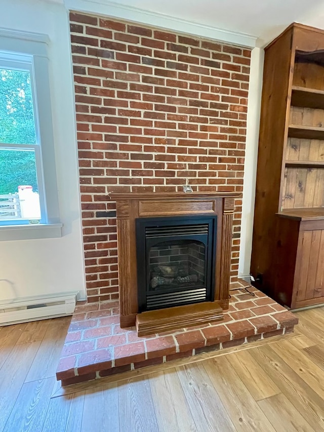 details with baseboard heating, wood-type flooring, and a brick fireplace