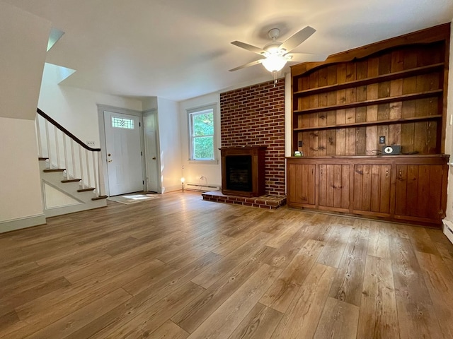 unfurnished living room featuring light hardwood / wood-style floors, a brick fireplace, ceiling fan, and a baseboard heating unit