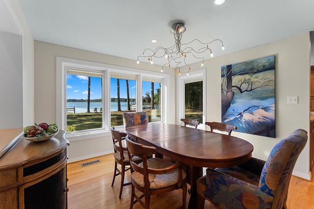 dining space featuring a chandelier, a water view, and light hardwood / wood-style floors