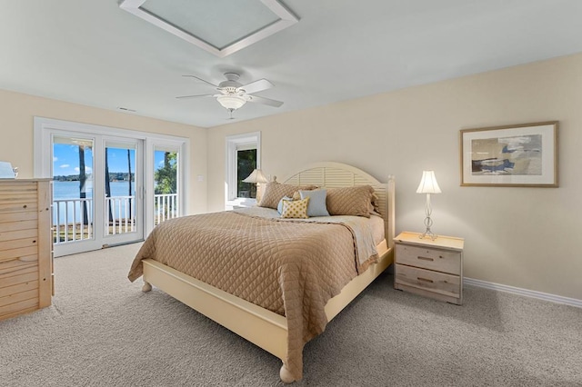 carpeted bedroom featuring access to exterior, a water view, and ceiling fan