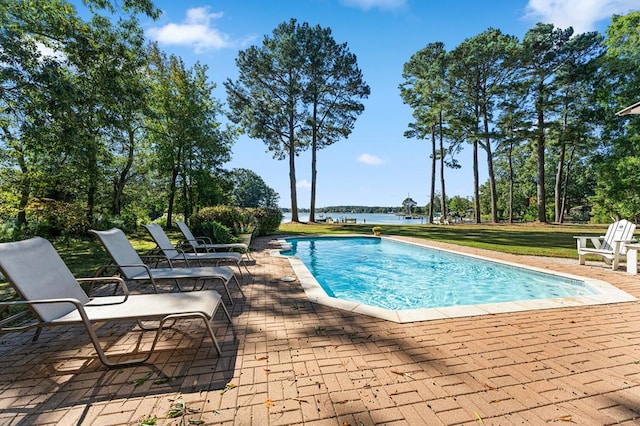 view of swimming pool featuring a water view, a lawn, and a patio area