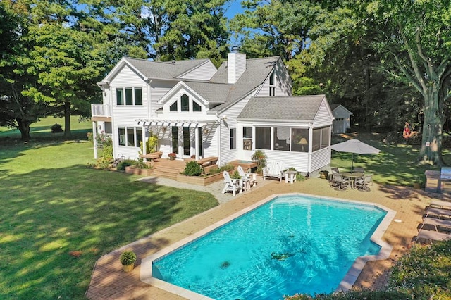 rear view of house featuring a sunroom, a patio area, a pool side deck, a lawn, and a pergola