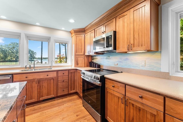 kitchen featuring sink, light wood-type flooring, appliances with stainless steel finishes, and decorative backsplash