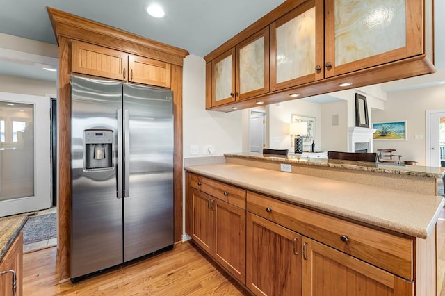 kitchen featuring light wood-type flooring, kitchen peninsula, and stainless steel refrigerator with ice dispenser